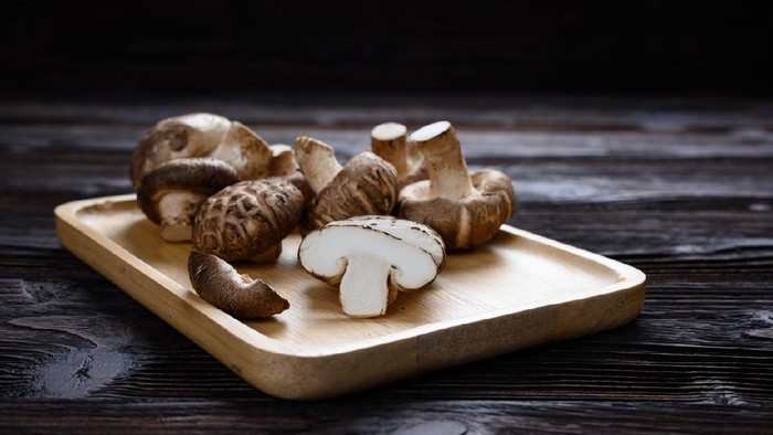 Shiitake mushrooms (Lentinus edodes) on the wooden background.