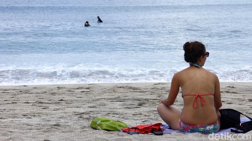 Ilustrasi wisatawan di pantai bali, berjermur, menikmati pantai.
