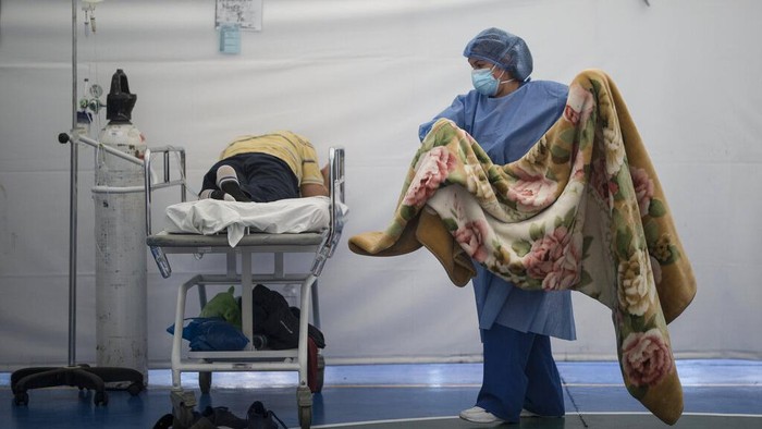 A healthcare worker tends to a COVID-19 patient in a tent set up on the soccer field of the Samaritana Hospital, in Bogota, Colombia, Thursday, June 3, 2021. Colombia has become a pandemic hotspot experiencing a third wave of COVID-19 infections and a surge in deaths. (AP Photo/Ivan Valencia)