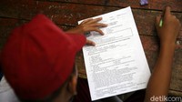 Seorang siswa tampak serius membaca soal-soal ujian. 