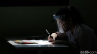 Seorang tampak serius membaca dan mengisi soal-soal ujian.