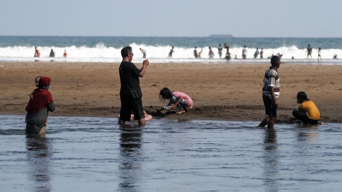 Wisatawan bermain air di kawasan Pantai Baron, Tanjungsari, Gunungkidul, DI Yogyakarta, Senin (7/6/2021). Destinasi wisata yang menawarkan pemandangan pantai dan kuliner makanan laut tersebut masih menjadi destinasi andalan di Gunungkidul. ANTARA FOTO/Hendra Nurdiyansyah/rwa.