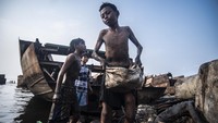 Sejumlah bocah mencari sisa besi bekas di lokasi kapal yang dibelah di Cilincing, Jakarta, Minggu (6/6/2021).   