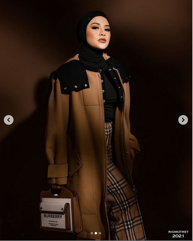 Tampilan modest nan modern ini dipadukan dengan celana dengan motif tartan ikonik Burberry serta blouse hitam. Foto: Instagram/@riomotret