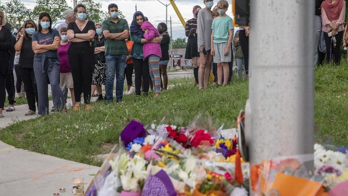 People attend a memorial at the location where a family of five was hit by a driver, in London, Ontario, Monday, June 7, 2021. Four of the members of the family died and one is in critical condition. A 20-year-old male has been charged with four counts of first degree murder and count of attempted murder in connection with the crime. (Brett Gundlock/The Canadian Press via AP)