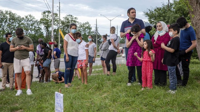 People attend a memorial at the location where a family of five was hit by a driver, in London, Ontario, Monday, June 7, 2021. Four of the members of the family died and one is in critical condition. A 20-year-old male has been charged with four counts of first degree murder and count of attempted murder in connection with the crime. (Brett Gundlock/The Canadian Press via AP)