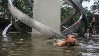 Anak-anak ini tampak riang gembira berenang meski bukan di kolam renang. Minimnya lahan bermain membuat anak-anak ini berenang di bawah Tugu Situ Gintung.