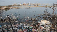 Warga memancing ikan di pantai yang penuh dengan sampah rumah tangga di Desa Branta Pesisir, Pamekasan, Jawa Timur, Selasa (8/6/2021).