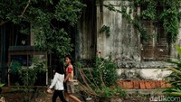 Dua orang warga melintas di depan bangunan tua yang berada di kawasan Tangerang Selatan, Selasa (8/6/2021).