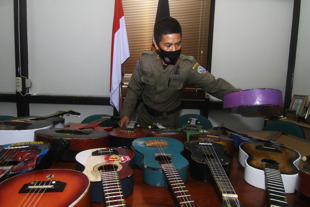 SATPOL PP RAZIA PENGAMEN JALANAN Petugas Satuan Polisi Pamong Praja (Satpol PP) Kota Pontianak memperlihatkan belasan alat musik petik hasil razia pengamen saat rilis di Mako Satpol PP Kota Pontianak, Kalimantan Barat, Senin (7/6/2021). Belasan alat musik petik berupa ukulele dan gitar tersebut merupakan hasil penjaringan dari pengamen di perempatan jalan yang telah meresahkan pengguna jalan dan mengganggu ketertiban umum. ANTARA FOTO/Jessica Helena Wuysang/rwa.