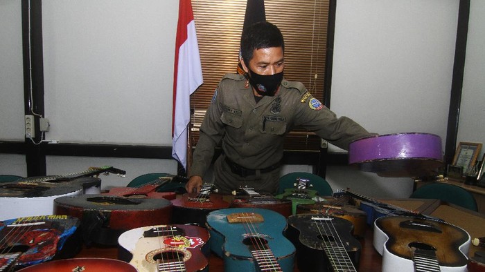 Petugas Satuan Polisi Pamong Praja (Satpol PP) Kota Pontianak memperlihatkan belasan alat musik petik hasil razia pengamen saat rilis di Mako Satpol PP Kota Pontianak, Kalimantan Barat, Senin (7/6/2021). Belasan alat musik petik berupa ukulele dan gitar tersebut merupakan hasil penjaringan dari pengamen di perempatan jalan yang telah meresahkan pengguna jalan dan mengganggu ketertiban umum. ANTARA FOTO/Jessica Helena Wuysang/rwa.