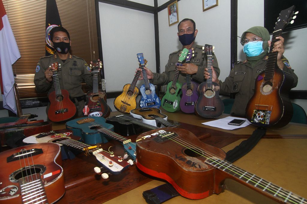 SATPOL PP RAZIA PENGAMEN JALANAN Petugas Satuan Polisi Pamong Praja (Satpol PP) Kota Pontianak memperlihatkan belasan alat musik petik hasil razia pengamen saat rilis di Mako Satpol PP Kota Pontianak, Kalimantan Barat, Senin (7/6/2021). Belasan alat musik petik berupa ukulele dan gitar tersebut merupakan hasil penjaringan dari pengamen di perempatan jalan yang telah meresahkan pengguna jalan dan mengganggu ketertiban umum. ANTARA FOTO/Jessica Helena Wuysang/rwa.