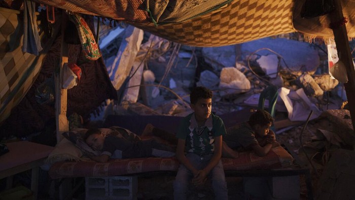 Warga Gaza Bertahan Hidup di Tengah Puing-puing Bangunan Palestinians look at the rubble of a building that collapsed after it was hit by airstrikes during an 11-day war between Gaza's Hamas rulers and Israel, in Gaza City, Tuesday, June 1, 2021. (AP Photo/Felipe Dana)