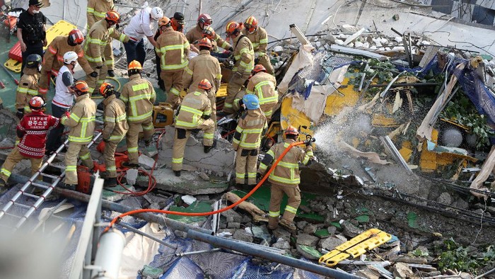 Firefighters search for survivors following a collapsed building in Gwangju, South Korea, Wednesday, June 9, 2021. A building being demolished in southern South Korea collapsed on Wednesday, sending debris falling on nearby vehicles and seriously injuring several people, officials said(Chung Hoi-sung/Yonhap via AP)