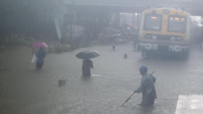 Banjir Hingga Bangunan Runtuh Gegara Hujan Lebat di India A man makes his way across flooded railway tracks during heavy rains in Mumbai, India, Wednesday, June 9, 2021. (AP Photo/ Rafiq Maqbool)