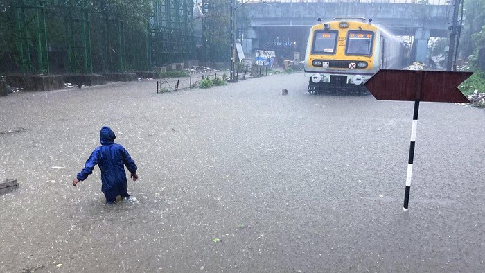 A man makes his way across flooded railway tracks during heavy rains in Mumbai, India, Wednesday, June 9, 2021. (AP Photo/ Rafiq Maqbool)