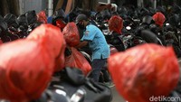 Tukang parkir tersebut memasukkan helm pemotor satu per satu di dalam kantong plastik yang ia siapkan.
