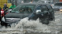 Air yang menggenangi jalan membuat para pengendara mobil dan motor melambatkan lajunya karena bagian mesin terendam.