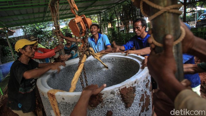 Para pekerja menurunkan gorong-gorong sumur resapan di halaman SMPN 43 Mampang Prapatan, Jakarta, Kamis (10/6/2021).