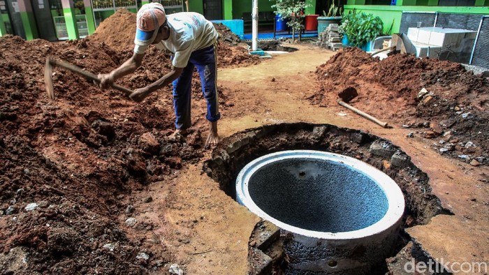 Para pekerja menurunkan gorong-gorong sumur resapan di halaman SMPN 43 Mampang Prapatan, Jakarta, Kamis (10/6/2021).