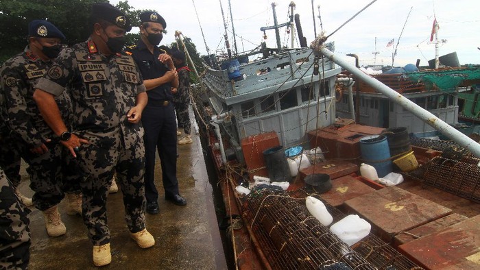 KKP TANGKAP 19 KAPAL PENCURI IKAN Dua petugas Kapal Pengawas Kementerian Kelautan dan Perikanan (KKP) bersiaga di kapal ikan ilegal hasil tangkapan di Stasiun Pengawasan Sumber Daya Kelautan dan Perikanan (PSDKP) Pontianak di Sungai Rengas, Kabupaten Kubu Raya, Kalimantan Barat, Kamis (10/6/2021). Sebanyak 19 kapal ikan ilegal berbendera Malaysia, Vietnam, Filipina dan Indonesia berhasil ditangkap lima kapal pengawas perikanan KKP saat melaksanakan operasi pengawasan di Laut Natuna Utara dan Laut Sulawesi pada 3-8 Juni 2021. ANTARA FOTO/Jessica Helena Wuysang/foc.