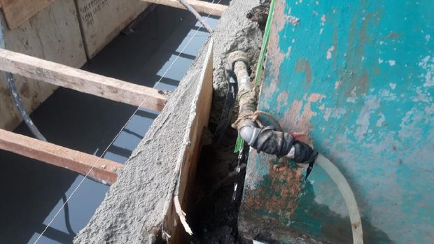 Warga Cakung Barat yang terdampak gangguan air PAM menyambung selang ke pipa yang tidak bermasalah.