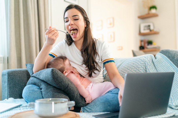 menyusui Young Mom Breastfeeding Baby While Working Remotely On Laptop At Home and eating