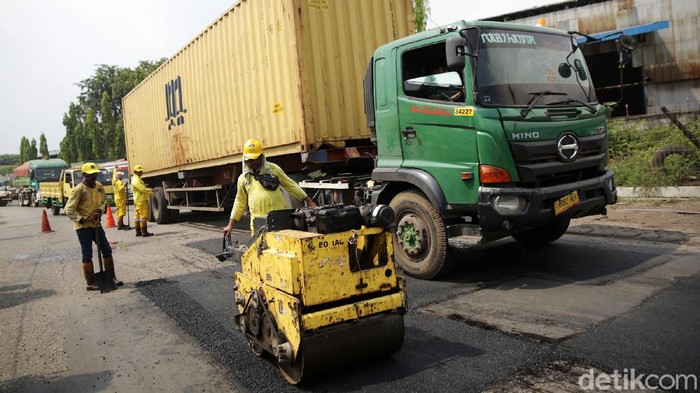 Petugas Bina Marga melakukan pengaspalan jalan yang berlubang di Jalan Akses Marunda, Jakarta Utara, Jumat (11/6/2021). Pengaspalan jalan yang sering rusak karena dilalui kendaraan berat ini dilakukan guna memberikan kenyamanan para pengguna jalan.