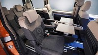 Ruang kabin VW Multivan T7 ini menyediakan meja yang bisa digeser bersamaan dengan kursi yang diputar 180 derajat hingga menjadi ruang meeting berjalan. Foto: Pool (Motor1)