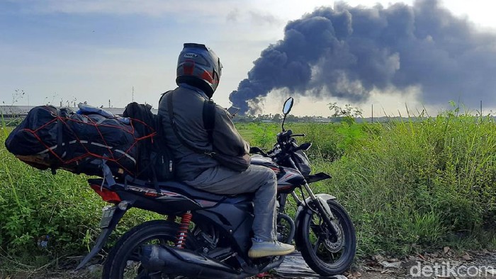 Kepulan asap yang membumbung ke arah barat dari tangki Kilang Pertamina RU IV Cilacap yang terbakar sejak Jumat (11/6) malam menjadi tontonan warga sekitar. Warga yang penasaran semakin sore semakin banyak.