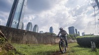 Pesepeda melaju dengan latar belakang gedung-gedung pencakar langit.