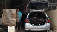 Seorang warga tengah membersihkan mobilnya yang terendam banjir.