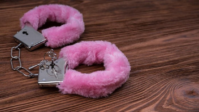 Handcuffs with pink fur on a wooden table. bdsm role play sexy