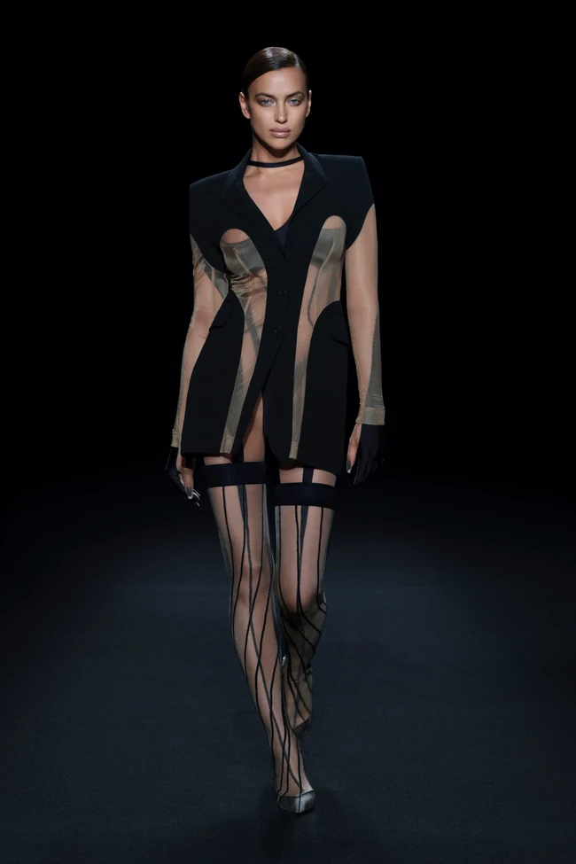 Di runway, penampilannya menjadi sedikit berbeda. Tampak bodysuit dibungkus dengan blazer hitam berpanel transparan yang menginjeksikan kesan elegan. Selain Irina Shayk tampil pula Bella Hadid. Tidak ketinggalan model yang juga bintang serial HBO Euphoria Hunter Schafer. (Foto: Dok. Mugler via Vogue)
