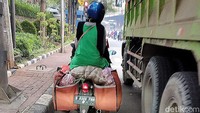 Seorang pengendara mengendarai motor yang tampak kelebihan muatan di kawasan Cawang, Jakarta Timur, Senin (14/6/2021).