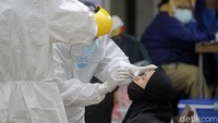 Petugas tampak mengambil sampel cairan hidung dari seorang warga untuk dites dan dilihat hasilnya.