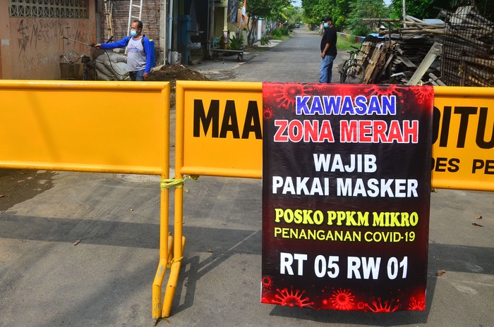 Petugas menyemprotkan disinfektan di sekitar jalan desa yang ditutup akibat karantina wilayah di Desa Pedawang, Kudus, Jawa Tengah, Selasa (1/6/2021). Akibat lonjakan tajam kasus COVID-19 pascalebaran di kabupaten itu, sebanyak 42 desa masuk zona merah COVID-19 dan menerapkan aturan Pemberlakuan Pembatasan Kegiatan Masyarakat (PPKM) skala mikro untuk mencegah penularan COVID-19. ANTARA FOTO/Yusuf Nugroho/rwa.