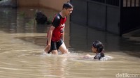 Dua orang anak tengah bermain di tengah banjir.