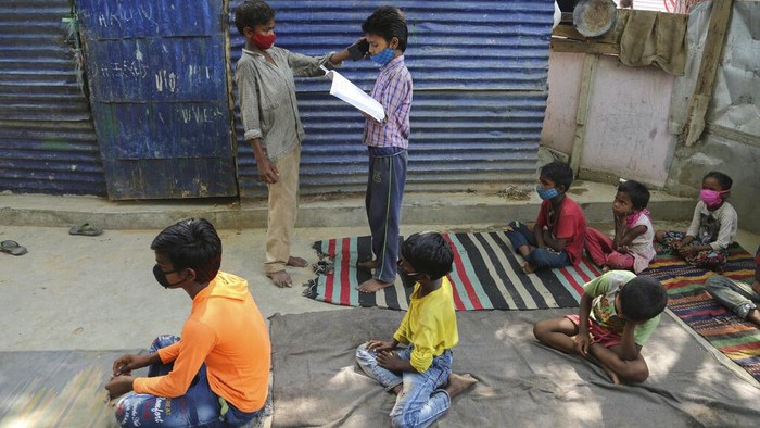 Kala Anak-anak Pemukiman Kumuh di India Ikut Kelas Online A teacher gestures as children wearing face masks as a precaution against the coronavirus attend online classes at a slum on the outskirts of Jammu, India, Monday, June 14, 2021. (AP Photo/Channi Anand)
