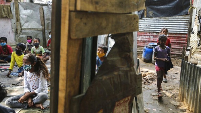 Kala Anak-anak Pemukiman Kumuh di India Ikut Kelas Online A teacher gestures as children wearing face masks as a precaution against the coronavirus attend online classes at a slum on the outskirts of Jammu, India, Monday, June 14, 2021. (AP Photo/Channi Anand)