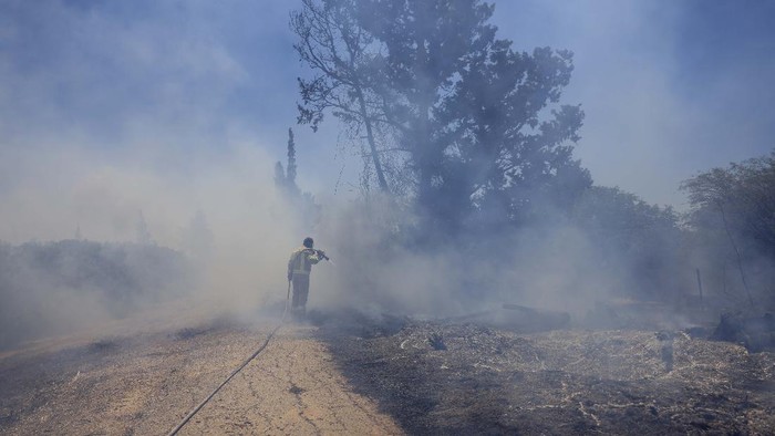 An Israeli firefighter attempts to extinguish a fire caused by an incendiary balloon launched by Palestinians from the Gaza Strip, on the Israel-Gaza border, Israel, Tuesday, June 15, 2021. (AP Photo/Tsafrir Abayov)