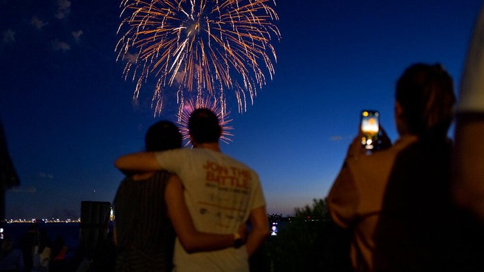 Pembatasan Dicabut, Warga New York Pesta Kembang Api Fireworks reflect off the water as they explode over New York Harbor and the Statue of Liberty as New York and other cities around New York state recognize a rate of 70% for single dose vaccinations against the COVID-19 virus, Tuesday, June 15, 2021 in New York. Celebration of the milestone was announced by Gov. Andrew Cuomo earlier in the day. (AP Photo/Craig Ruttle)