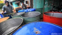 Dua karyawan tampak sibuk melubangi tong sebelum proses pengecatan.