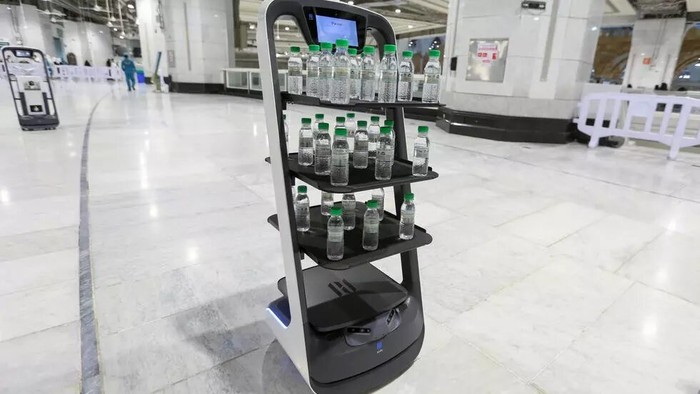 Rolling robots have been deployed to ensure pilgrims have access to holy water without human contact - AFP