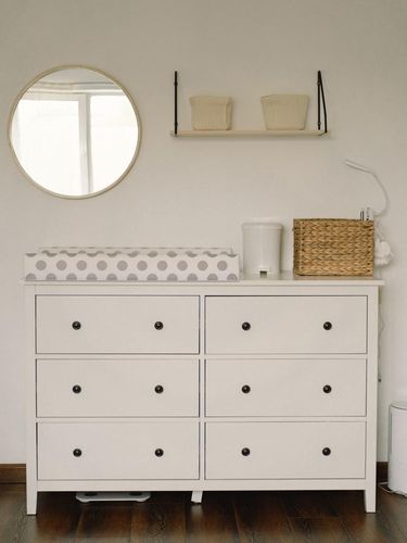 Baby room interior design. Chest of drawers with changing pad and tray in nursery. Infant baby room.