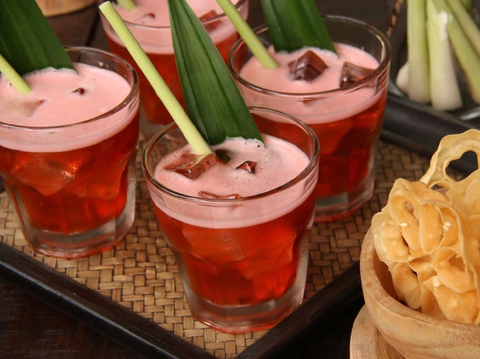 Bir Pletok, the traditional non-alcoholic beer from Betawi culture, Jakarta. The beer, that is basically a herbal concoction, is served with foam on top after being shaken with ice cubes. The beer is served in a old-fashioned glass filled with ice cubes and garnished with lemongrass and pandan leaf. Served with traditional snack also from Betawi, Jakarta.