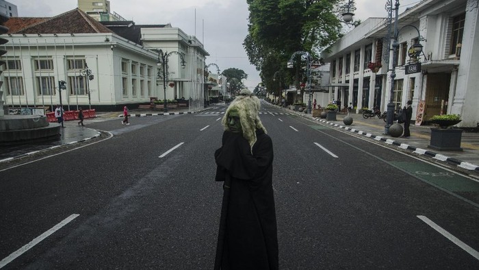 Cosplayer hantu berdiri di tengah ruas jalan protokol kawasan Asia Afrika yang ditutup di Bandung, Jawa Barat, Jumat (18/6/2021). Warga menikmati suasana ruas jalan protokol di Kota Bandung yang lengang setelah ditutup untuk menekan peningkatan kasus aktif COVID-19 dan status siaga satu kawasan Bandung Raya. ANTARA FOTO/Novrian Arbi/rwa.