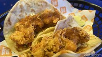 Sensasi kriuk renyah dari ayam gorengnya langsung disambut dengan tortilla hangat yang masih terasa serat rotinya. Rasa daging ayamnya cenderung manis gurih, cocok dengan sengatan asam segar dari salsa al pastor yang sedikit pedas. Sementara lelehan keju mozarellanya menjadi pelengkap cita rasa taco yang apik dan bikin nagih. Foto: detikFood