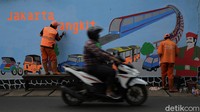 Sejumlah petugas PPSU menyelesaikan mural di salah satu dinding jalan yang berada di kawasan Halim Perdanakusuma, Jakarta, Jumat (18/6/2021).  