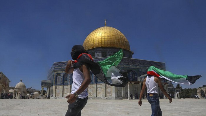 Masked Palestinians wearing the Palestinian flag during clashes with Israeli security forces stand n front of the Dome of the Rock Mosque at the Al Aqsa Mosque compound in Jerusalem's Old City, Friday, June 18, 2021. Hundreds demonstrated after Friday prayers in response to a rally held by Jewish ultranationalists on Tuesday in which dozens had chanted 